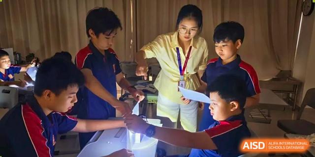 Students and a teacher gathered around a light table, using tablets or devices for collaborative digital learning in a technology-rich setting at Concordia International School Ningbo.