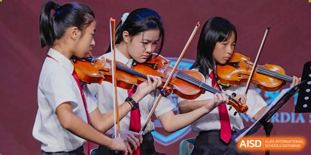 Two female students intensely playing violins side-by-side during a performance, recital, or music lesson at Concordia International School Ningbo.