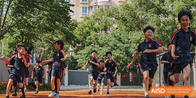 A group of students running and exercising outdoors in a park or schoolyard on a sunny day, showcasing fitness activities at Concordia International School Ningbo.