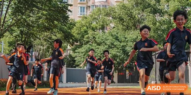 A group of students running and exercising outdoors in a park or schoolyard on a sunny day, showcasing fitness activities at Concordia International School Ningbo.
