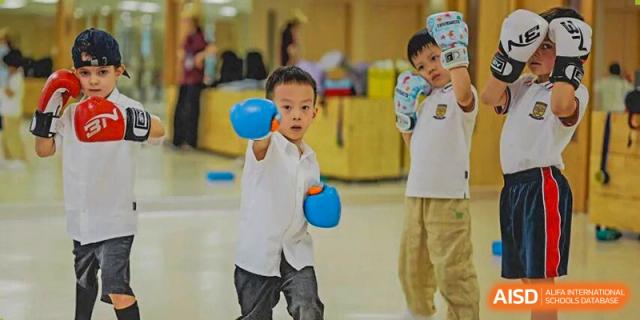 A young student participating in a hands-on activity indoors, possibly holding a blue ball, engaged in an interactive class at Concordia International School Ningbo.