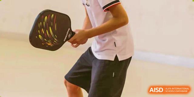 A close-up of a student in athletic wear holding a paddle for racket sports, indicating physical education activities at Concordia International School Ningbo.