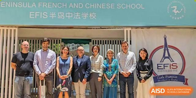 Five staff members and teachers stand together for a formal group photo in front of the school entrance at École Française Internationale de Shenzhen(EFIS).