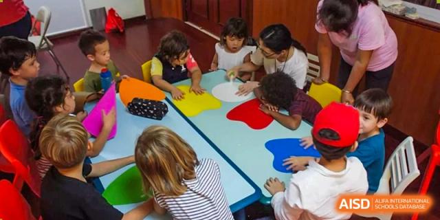 A teacher guides a group of small children through a creative art project at a colorful table at École Française Internationale de Shenzhen(EFIS).