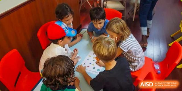 A group of students huddle together at a table to collaborate on a learning worksheet at École Française Internationale de Shenzhen(EFIS).