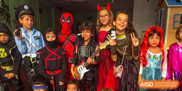 A group of children posing in rockstar and superhero outfits with a toy guitar at École Française Internationale de Shenzhen(EFIS).