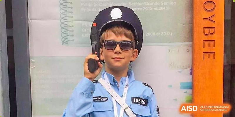 A young boy wearing sunglasses and a light blue police officer costume holding a toy walkie-talkie at École Française Internationale de Shenzhen(EFIS).