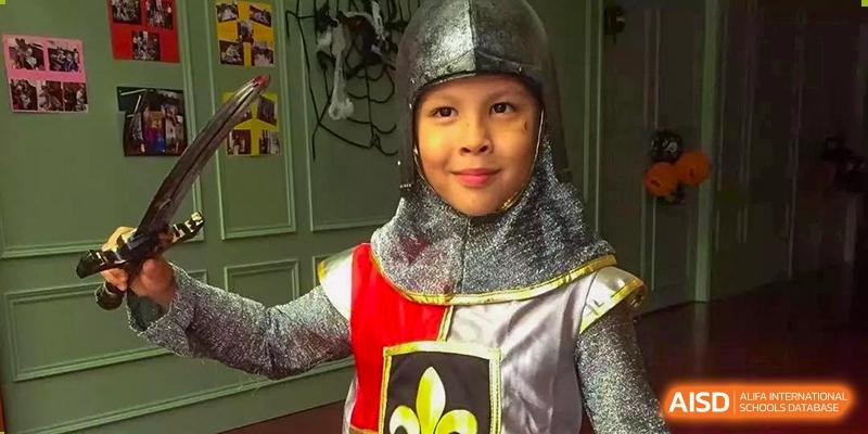 A young student smiling while dressed in a silver and gold knight costume during an event at École Française Internationale de Shenzhen(EFIS).