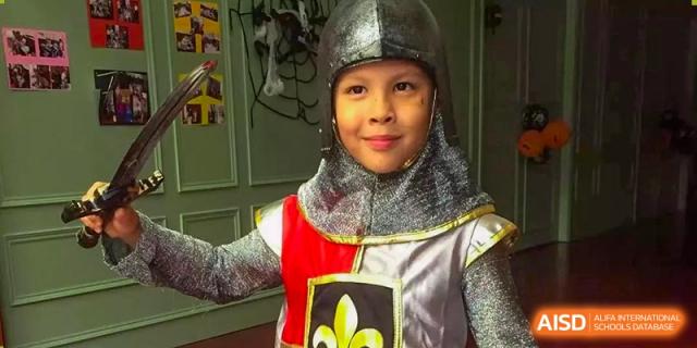 A young student smiling while dressed in a silver and gold knight costume during an event at École Française Internationale de Shenzhen(EFIS).