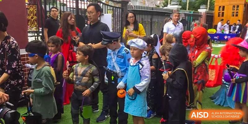 A group of students in costumes, including a police officer and a chef, waiting outdoors at École Française Internationale de Shenzhen(EFIS).