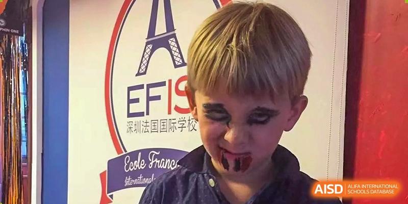 Close-up of a student with spooky face paint posing in front of a school banner at École Française Internationale de Shenzhen(EFIS).
