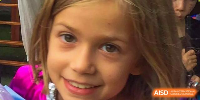 A close-up portrait of a smiling young girl during a festive celebration held at École Française Internationale de Shenzhen (EFIS).