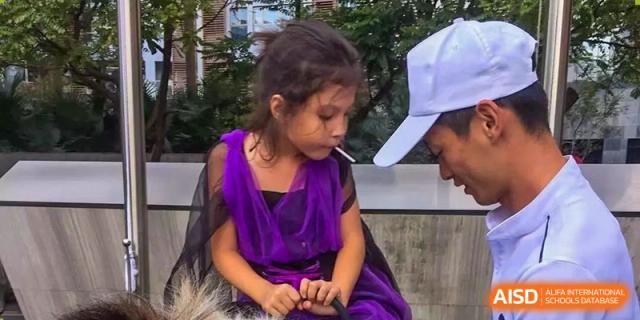 A young girl in a purple dress interacts with a pony during a school event at École Française Internationale de Shenzhen(EFIS).