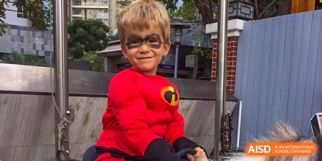 A young boy dressed in an Incredibles superhero costume smiles for a photo at École Française Internationale de Shenzhen(EFIS).
