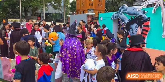 A person in a purple and gold witch costume stands among a crowd of students at École Française Internationale de Shenzhen(EFIS).