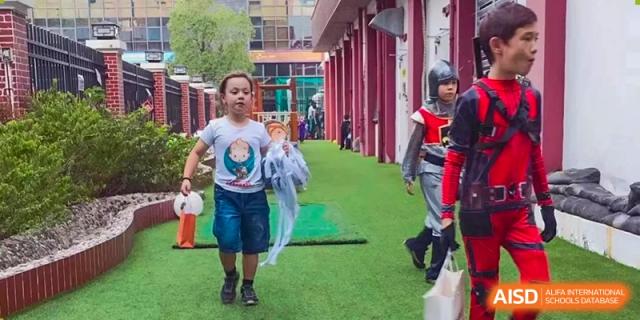 Students walk across a green turf area during a costume parade at École Française Internationale de Shenzhen(EFIS).