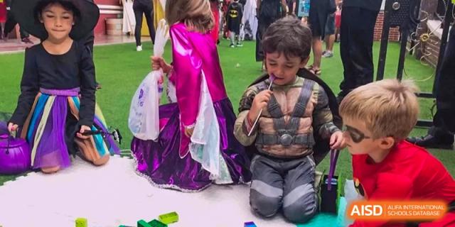 Two children in costumes sit on the floor during a festive school celebration at École Française Internationale de Shenzhen(EFIS).