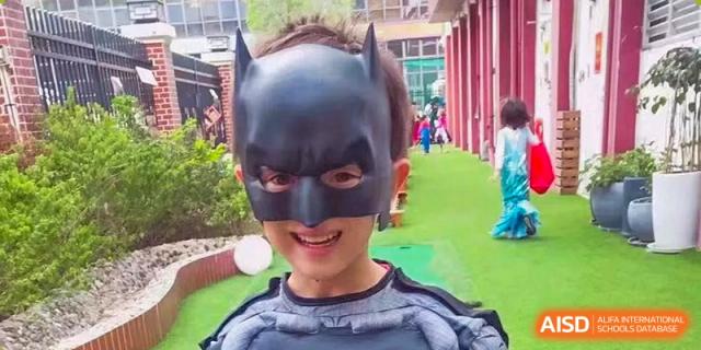 A young student wearing a black Batman mask smiles while playing outdoors at École Française Internationale de Shenzhen(EFIS).
