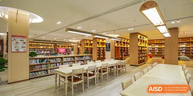 A wide shot of a spacious, quiet school library reading room with rows of tables and chairs ready for students, Hefei Xinhua Academy.
