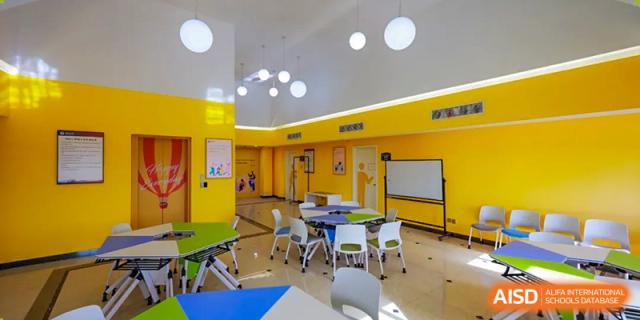 A colorful, well-lit classroom or activity room with small tables and chairs, designed for younger students, Hefei Xinhua Academy.