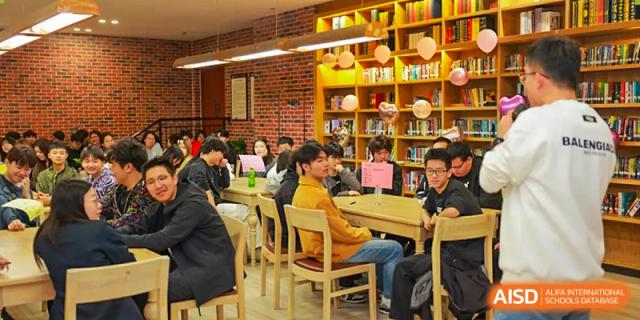 Students are seated around tables in a warm, brick-walled study area within the school's library or reading room, Hefei Xinhua Academy.