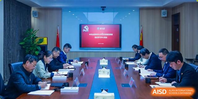 Adults seated around a long table in a formal conference room with a large screen displaying information at the front, Hefei Xinhua Academy.