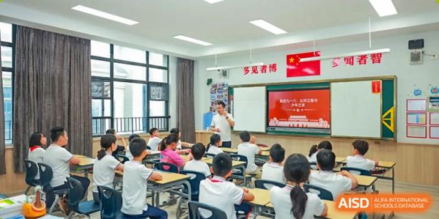 A teacher instructing a classroom full of elementary school students who are seated at their desks, Hefei Xinhua Academy.