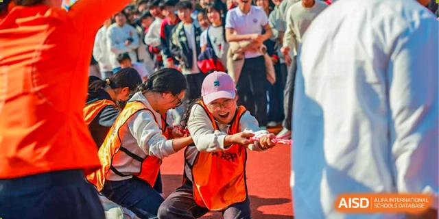 A close-up action photo of students straining and pulling with great effort during a spirited game of tug-of-war, showcasing their teamwork and determination during a lively inter-class sports event at Hefei Xinhua Academy.