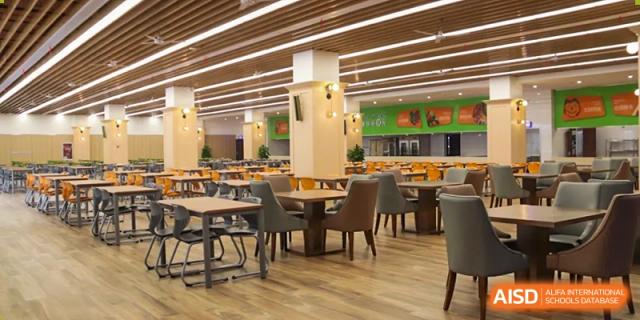 The interior of a large, modern, and brightly lit school cafeteria features many neatly arranged tables and comfortable chairs at Hefei Xinhua Academy.