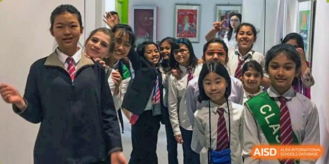 A group of smiling students from Pakistan Embassy College Beijing in their school uniforms gathered for a photo indoors.
