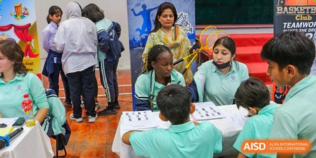 A teacher and students from Pakistan Embassy College Beijing participating in a board game or indoor activity in the gymnasium.