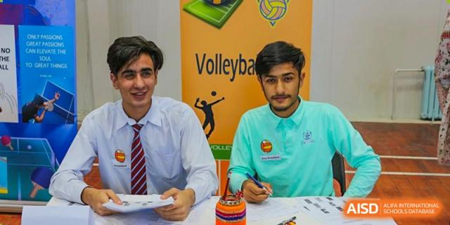 Two male students from Pakistan Embassy College Beijing, one in a tie, posing with a certificate at a sports club event.