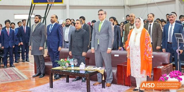 A formal gathering of officials and dignitaries at an event hosted by Pakistan Embassy College Beijing, standing by a table.