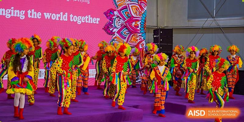 A group of young students from Pakistan Embassy College Beijing performing a vibrant cultural dance in colorful costumes.