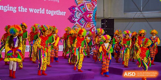 A group of young students from Pakistan Embassy College Beijing performing a vibrant cultural dance in colorful costumes.