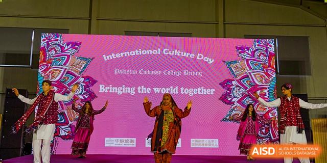 A student from Pakistan Embassy College Beijing performing a solo dance in a red costume on stage at 'International Culture Day'.