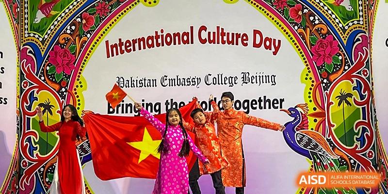 Three students from Pakistan Embassy College Beijing in traditional dress holding the Vietnamese flag at 'International Culture Day'.