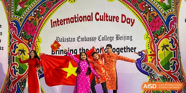 Three students from Pakistan Embassy College Beijing in traditional dress holding the Vietnamese flag at 'International Culture Day'.