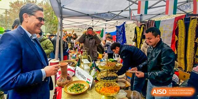 A busy food stall with various colorful dishes and people serving at the 'International Culture Day' event at Pakistan Embassy College Beijing.