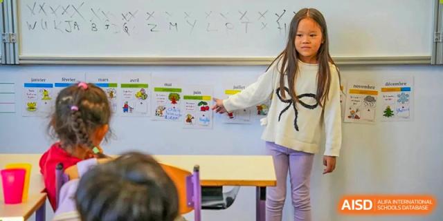 Girl pointing to an English alphabet and picture chart on the whiteboard at Proviseur, du Lycée Français International de Pékin.