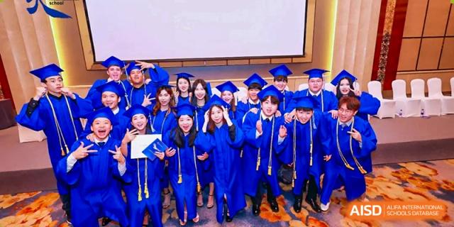 High school graduates in blue caps and gowns celebrate their achievement during a ceremony at Tianjin International School (TIS).