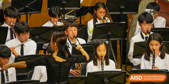 Middle school students playing instruments in an orchestral ensemble, including saxophones and clarinets, at Tianjin International School (TIS).