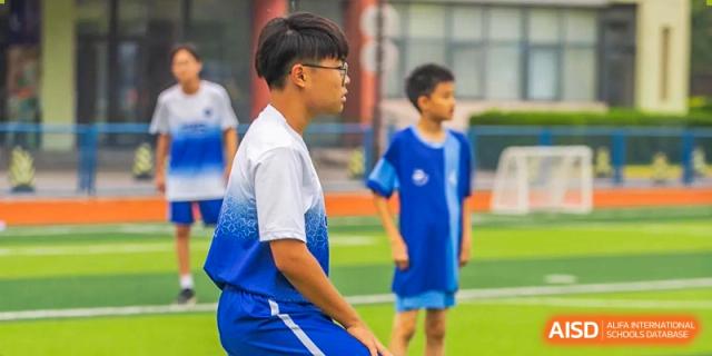 Close-up of a student athlete in a blue and white gradient sports jersey standing on an outdoor field at Tianjin International School (TIS).