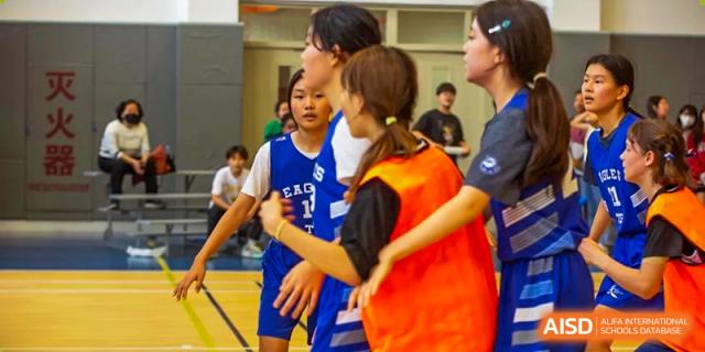 Basketball players in blue jerseys stand together on the court sideline during a break in the game at Tianjin International School (TIS).