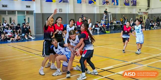 Female basketball players compete for the ball during a high-energy game in the gymnasium at Tianjin International School (TIS).