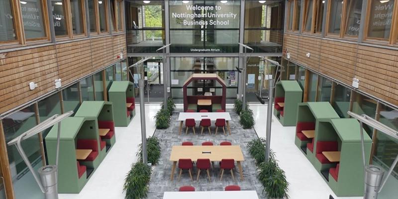 The bright, modern interior common space of the Normanton Community Business School is visible, designed with seating and tables for student study and collaboration at Maple Leaf International School Shanghai.