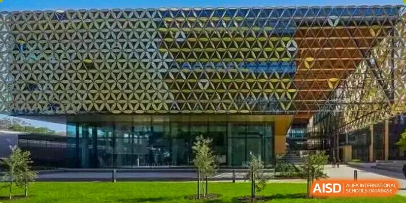A close-up view of a modern building showcases its distinctive facade, which is clad in an intricate geometric pattern of interconnected yellow and dark panels at Maple Leaf International School Shanghai.