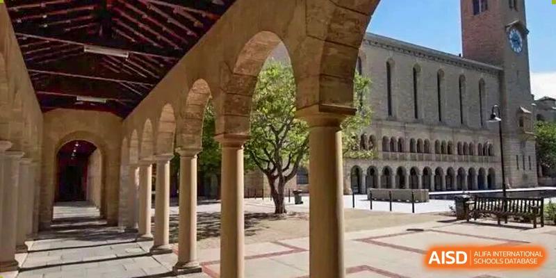 An architectural view showcases a covered walkway or cloister with several stone arches and columns near a stately academic building at Maple Leaf International School Shanghai.