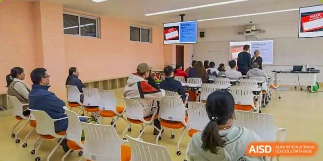 Students attend a class or seminar in a classroom setting, sitting in chairs while viewing a presentation displayed on a large screen at Maple Leaf International School Shanghai.