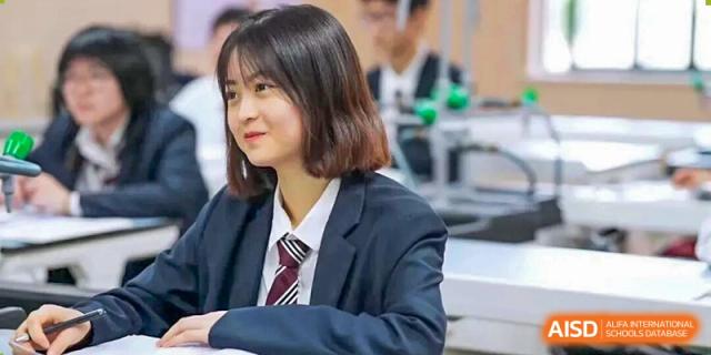 A cheerful female student in a uniform blazer and tie smiles confidently while positioned in a modern science laboratory at Living Word Shanghai.